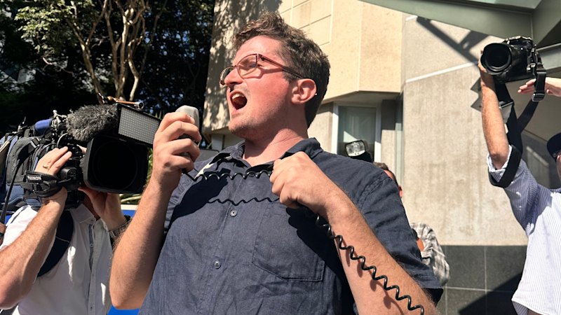 Protester twists banned phrase as crowd rallies for hate-speech accused