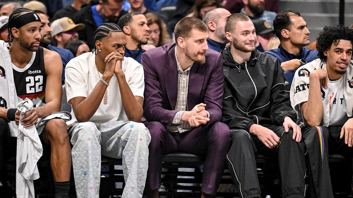Zeke Nnaji, Peyton Watson, Nikola Jokic, Christian Braun and Julian Strawther sitting on the bench during a basketball game.