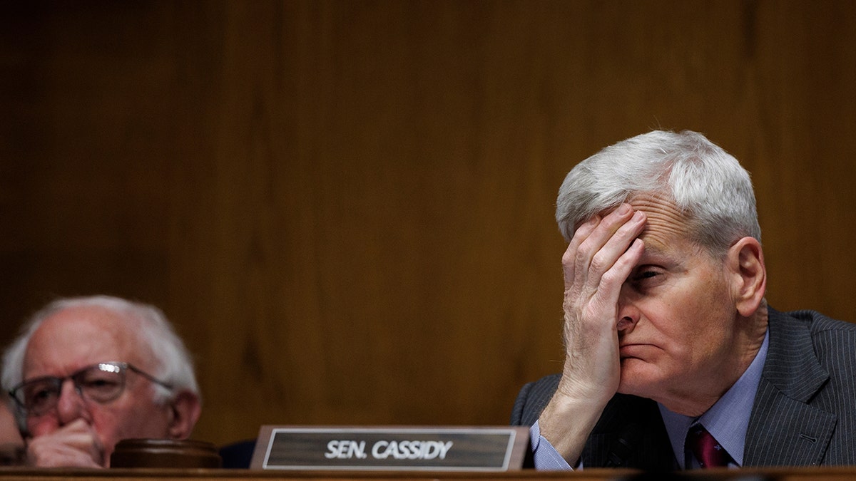 Senator Bill Cassidy holding his head during a Senate committee hearing in Washington