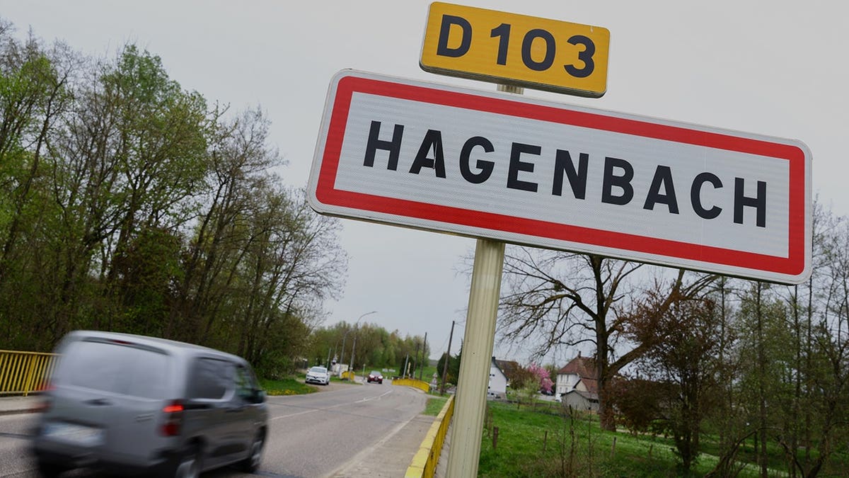 A car driving past a road sign at the entrance of Hagenbach