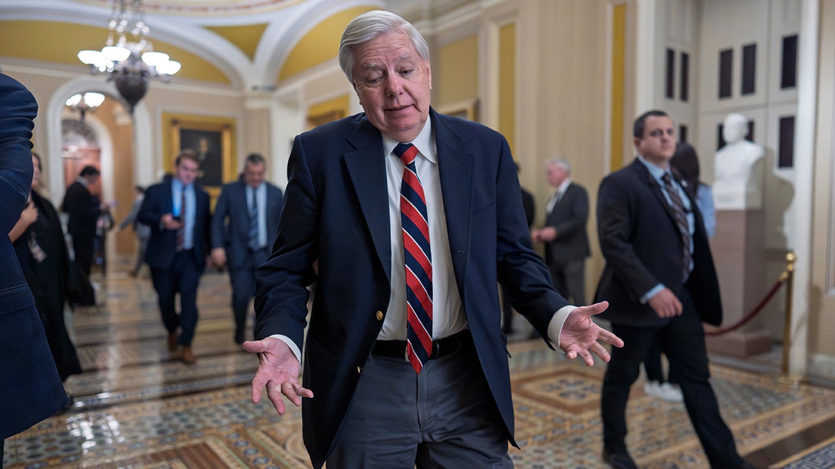 Lindsey Graham walking through a hallway toward the chamber.