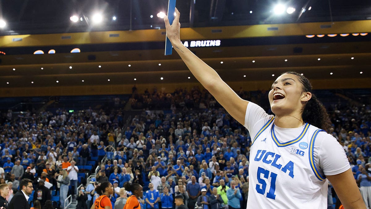 UCLA center Lauren Betts holding up a UCLA bracket sticker and reacting