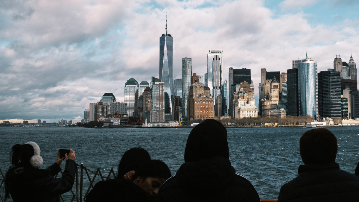 Commuters on Staten Island ferry with One World Trade Center and Manhattan skyline in background