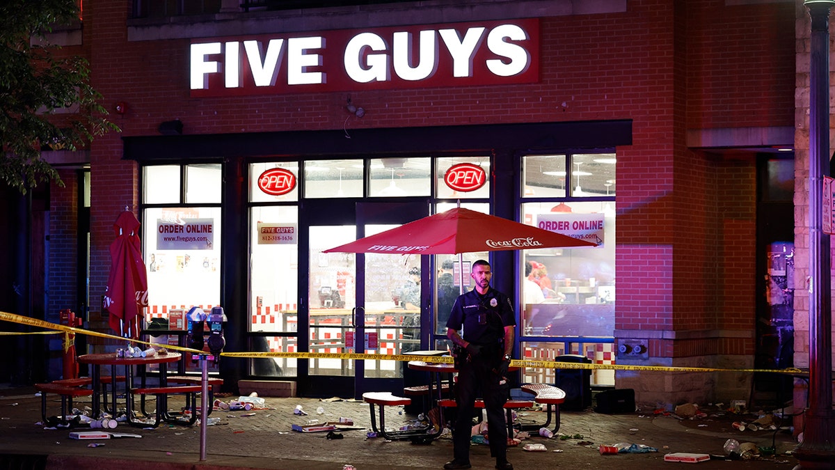A police officer stands on patrol outside a Five Guys store in bloomington