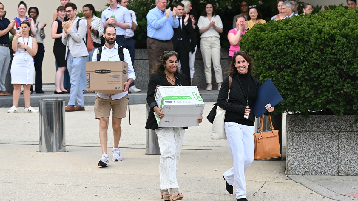 State Department workers carrying belongings leaving building in Washington, D.C.