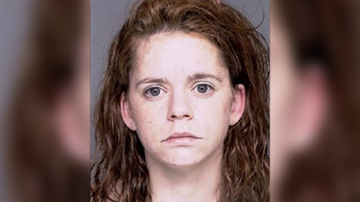 Valerie Mack with wavy red hair frowning in a portrait