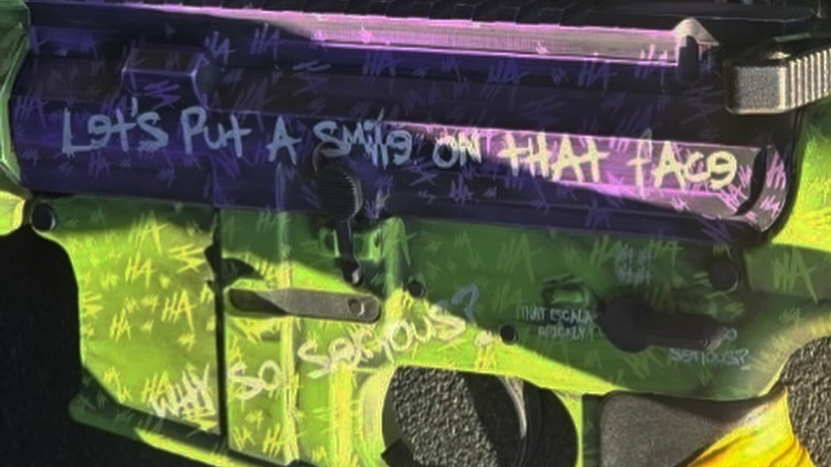 Green and purple painted AR-style rifle emblazoned with phrases including