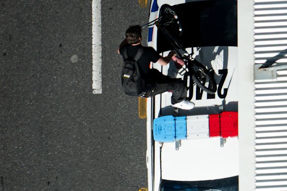 A protester rides his bike over a police car.