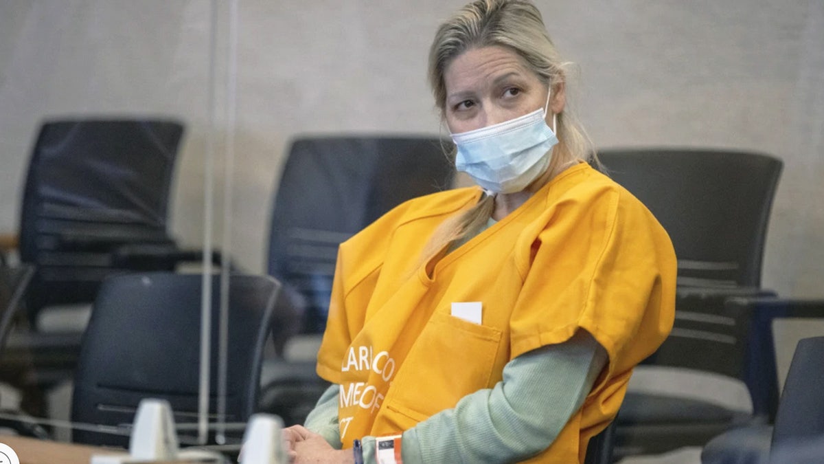 Shannon O'Connor sitting at defense table in yellow jail-issue jumpsuit in courtroom