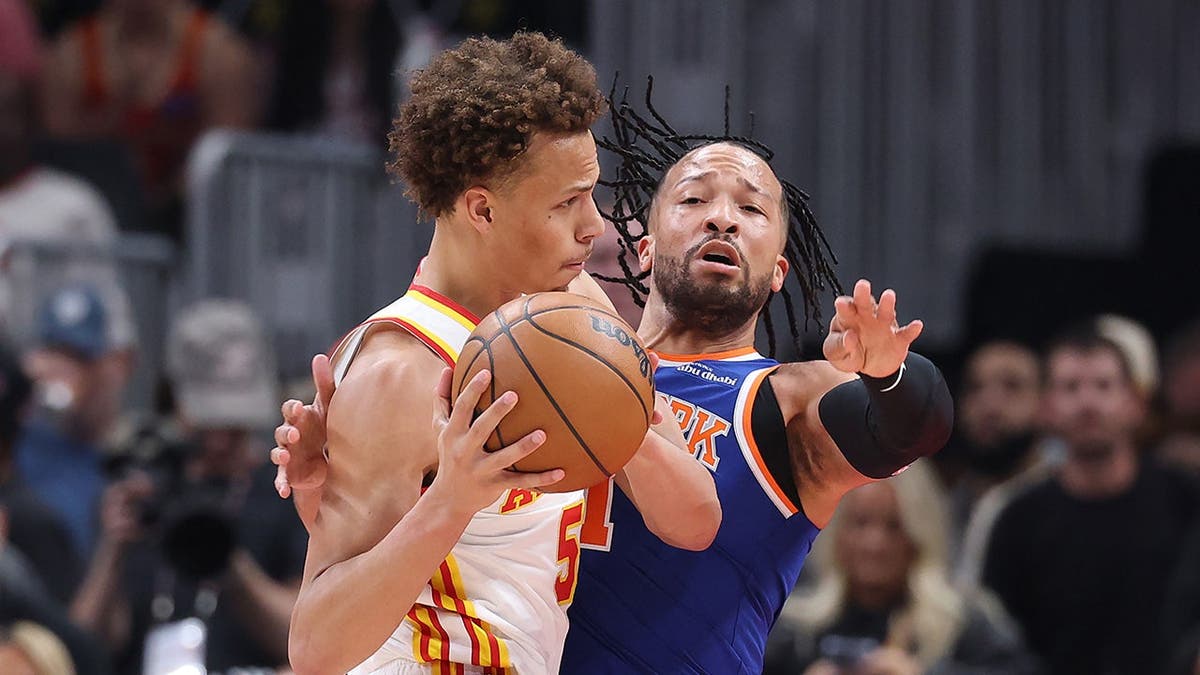 Dyson Daniels driving past Jalen Brunson during NBA playoff game in Atlanta