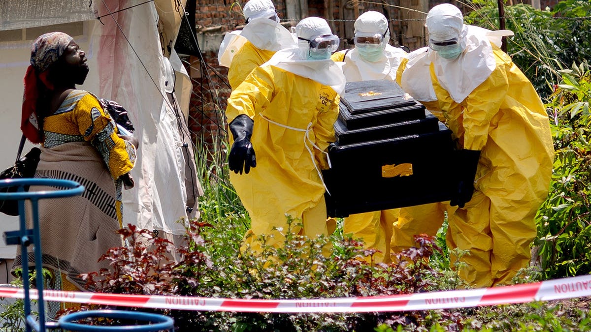 A woman crying as Red Cross workers carry a coffin outside a health center