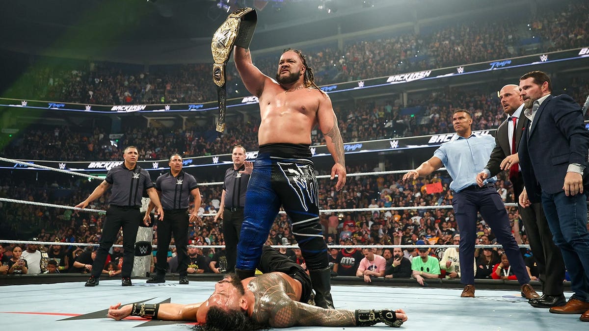 Jacob Fatu celebrating over Roman Reigns in a wrestling ring