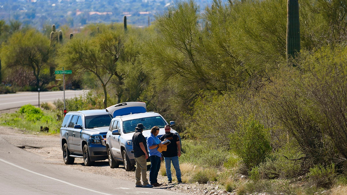 Law enforcement personnel looking near a roadway outside Nancy Guthrie's neighborhood in Catalina Foothills Tucson