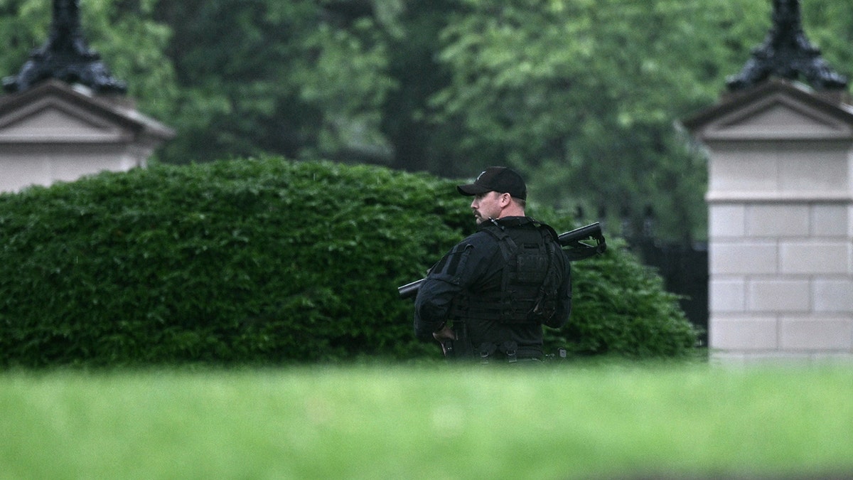 An armed Secret Service agent looks on at the White House