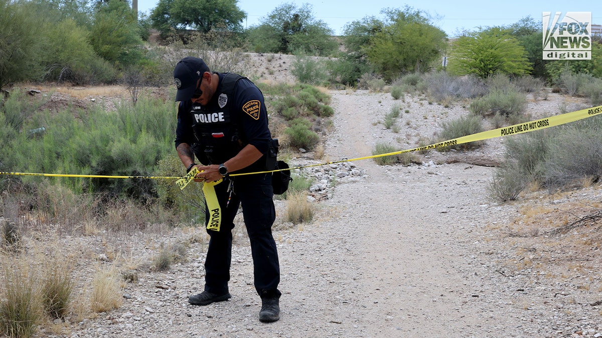 A Tucson police officer puts up police tape near where human remains were found in an ephemeral river while searching for Nancy Guthrie, the 84-year-old mother of "Today" co-host Savannah Guthrie.