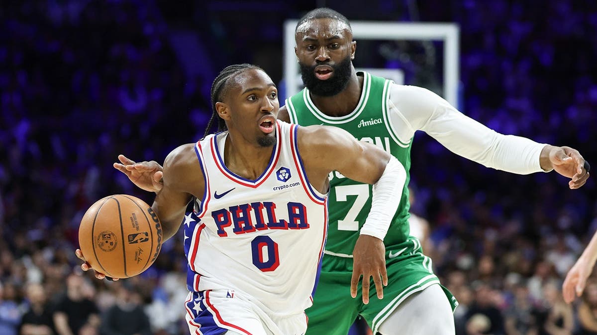 Tyrese Maxey driving past Jaylen Brown during a basketball game at Xfinity Mobile Arena