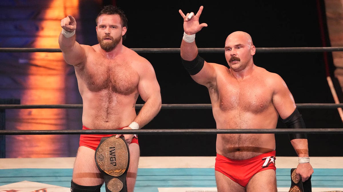 Cash Wheeler and Dax Harwood celebrating victory in a wrestling ring.