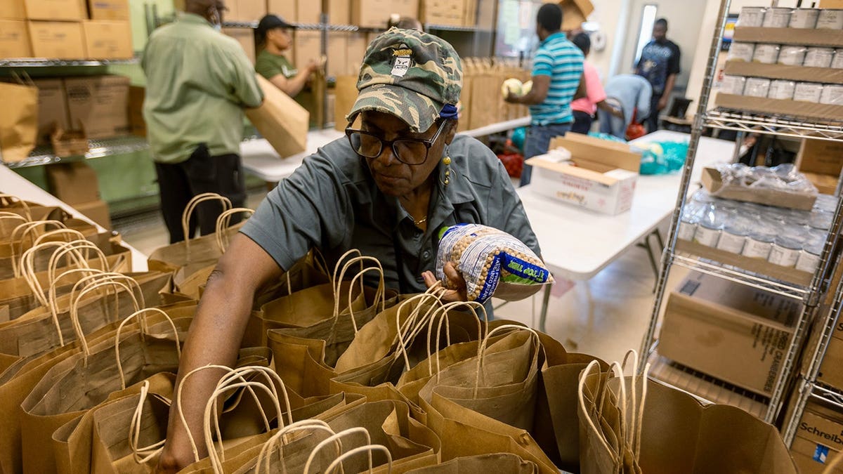 A woman is packing brown paper bags at a food warehouse