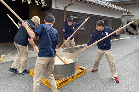 Matt Froude, wearing beanie, with co-workers, pounding rice at Matsuse sake brewery in Shiga prefecture in Japan.