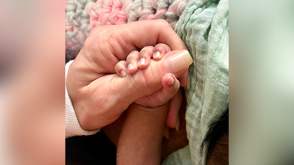 A baby hand held by an adult hand