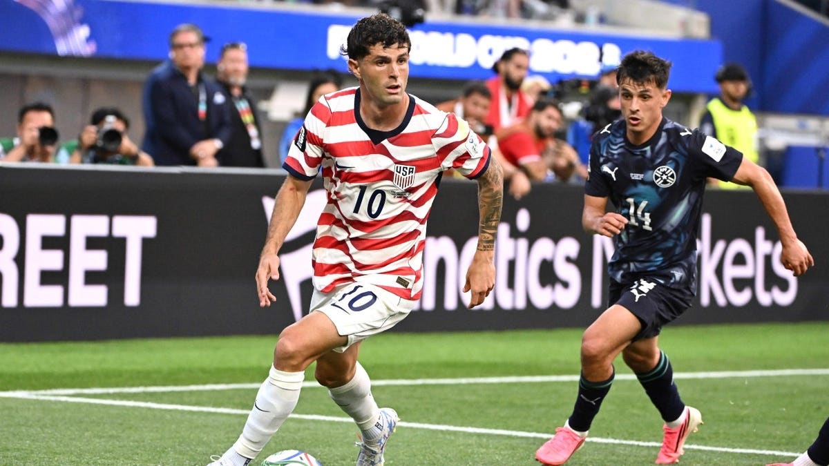 United States forward Christian Pulisic controls the ball past Paraguay midfielder Andrés Cubas in the first half of a FIFA World Cup 2026 match at SoFi Stadium in Los Angeles.