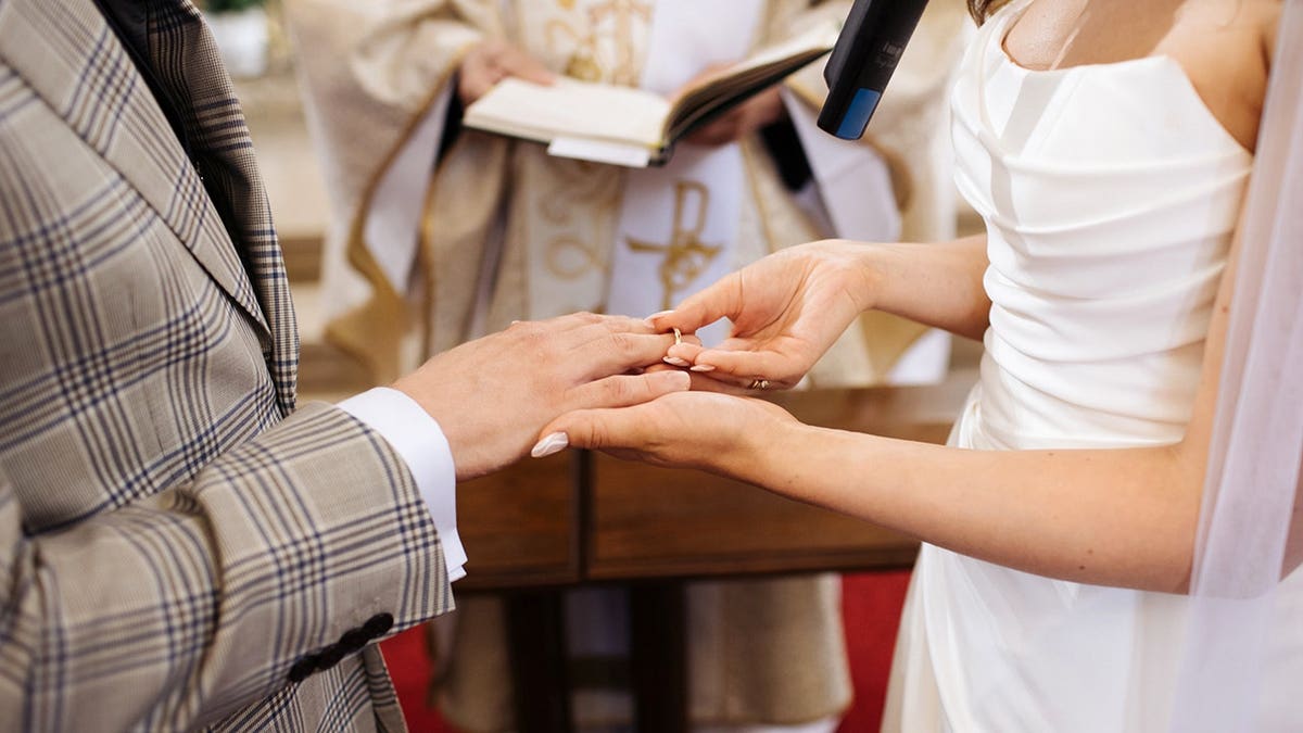Priest blessing couple during marriage ceremony in church.