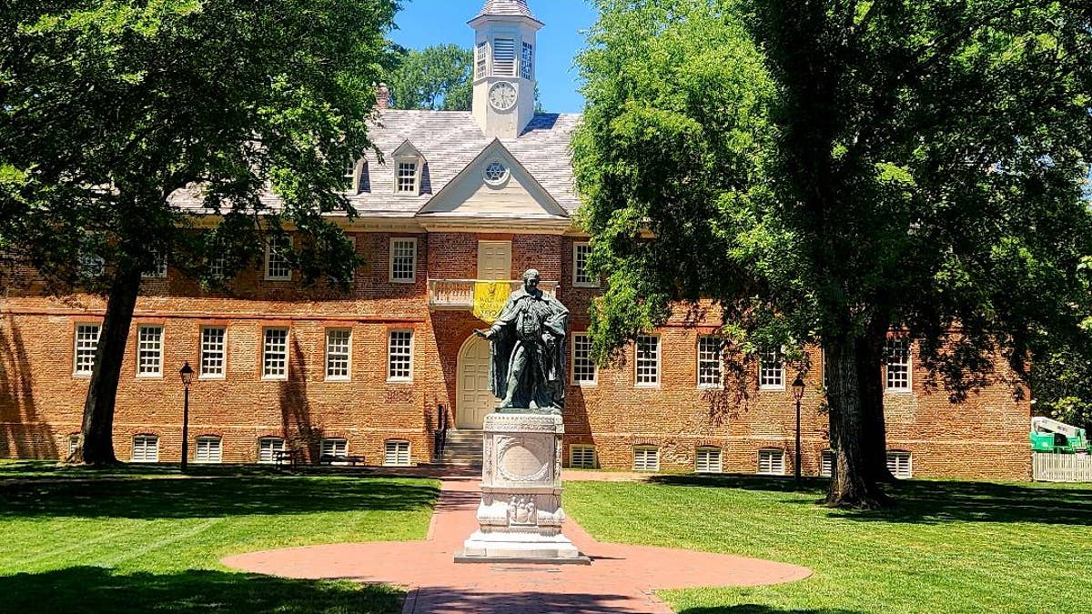 A statue stands in front of the College of William & Mary.
