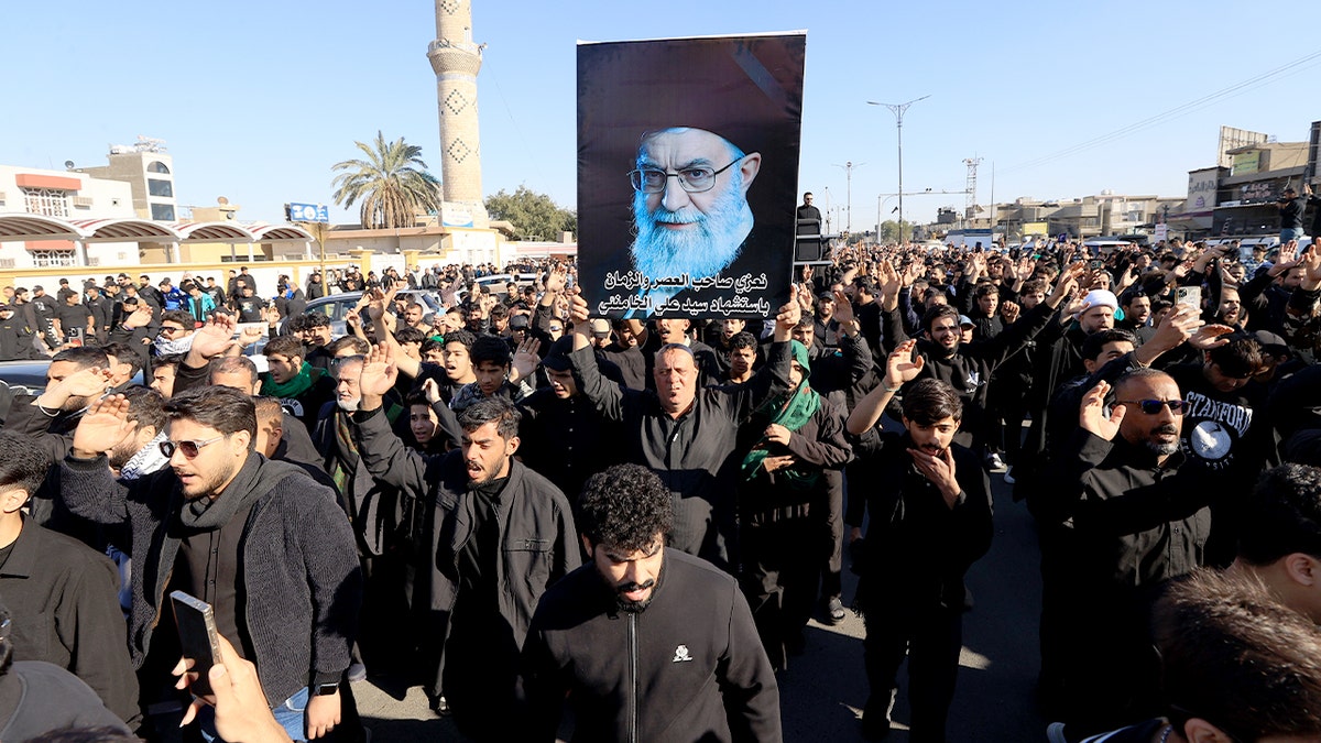 Supporters holding Iranian flags and portraits of Ayatollah Ali Khamenei in Baghdad's Sadr district