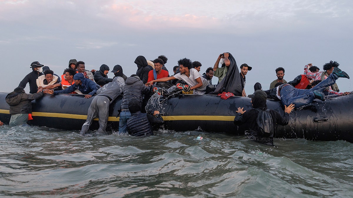 Migrants wading into water near Gravelines, France, with traffickers managing the scene