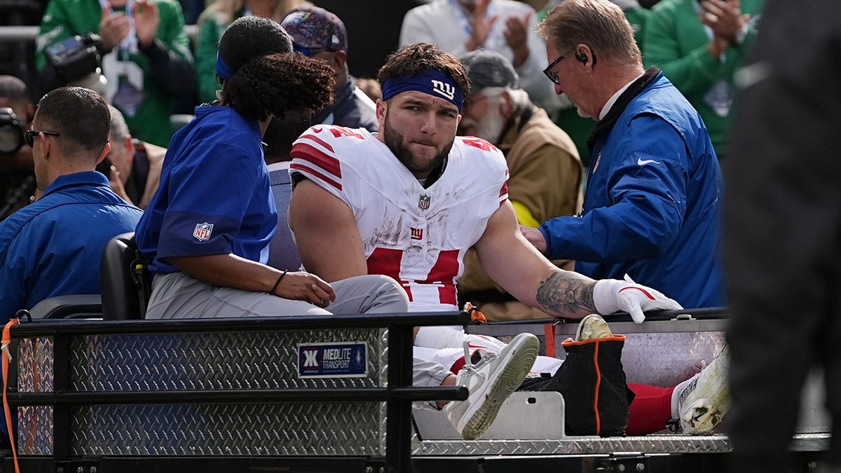 New York Giants running back Cam Skattebo walking off the field after an injury during a football game.