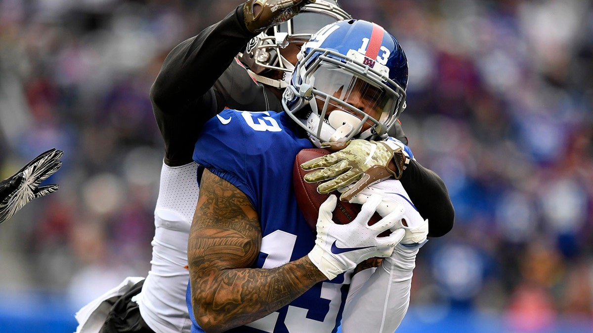 Odell Beckham Jr. catching football under pressure from Isaiah Johnson during game.