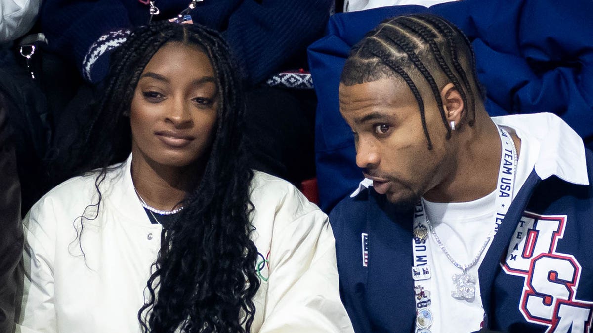 Simone Biles and Jonathan Owens seated at Milano Ice Skating Arena watching men's single skating event