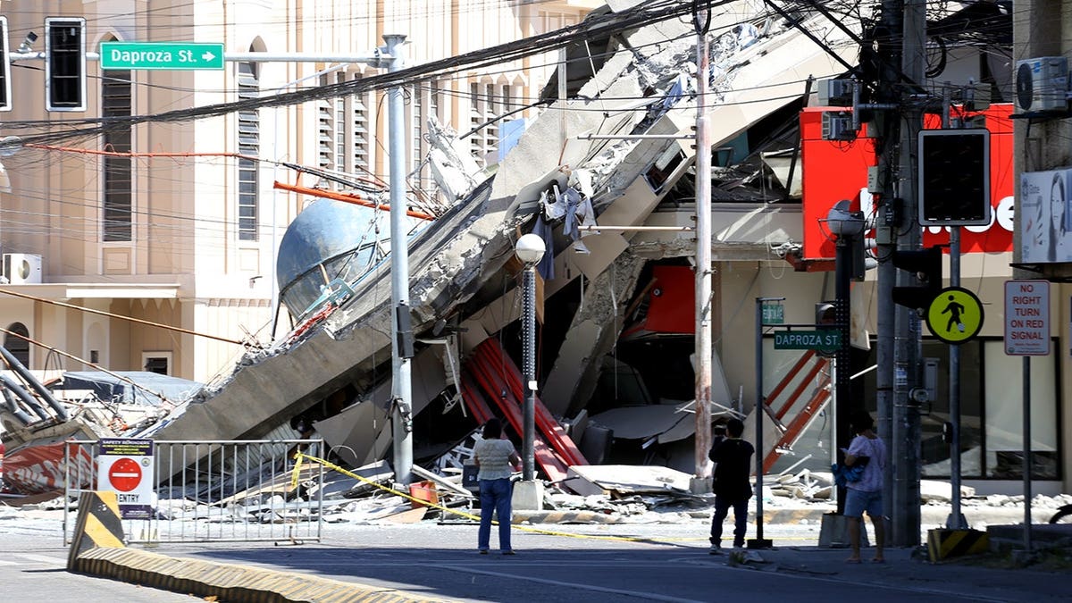 Onlookers look at a collapsed building.