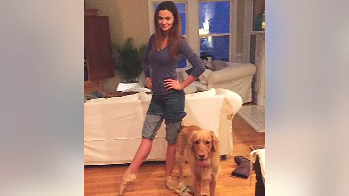 Ashley Benefield in a ballet position with her dog.