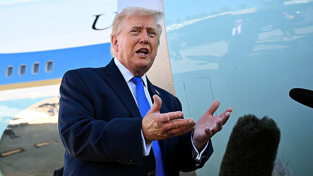 Donald Trump speaking to reporters while standing outdoors at an airport.