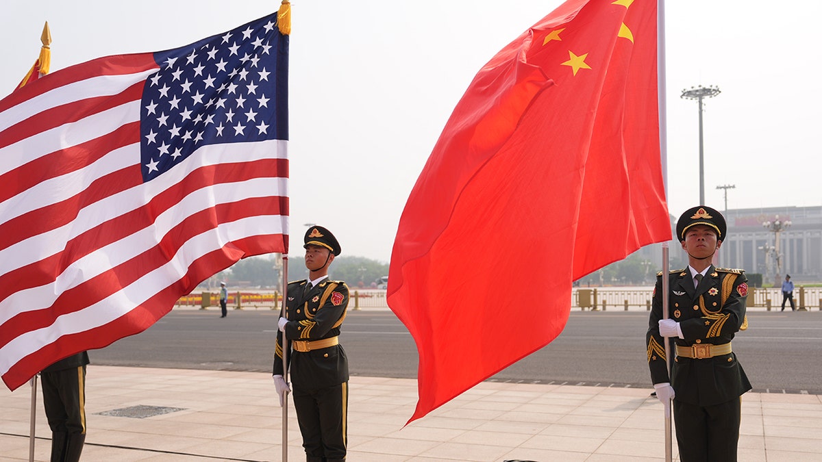 Members of a military honor guard hold the United States and Chinese flags outdoors.