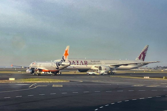 A Jetstar plane and a Qatar Airways plane on the runway at Sydney Airport on Sunday morning.