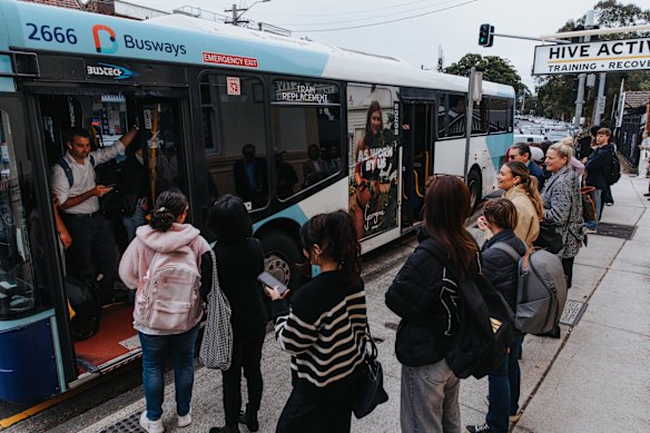 Commuters stand in long queues for replacement buses on the Pacific Highway at Roseville. 