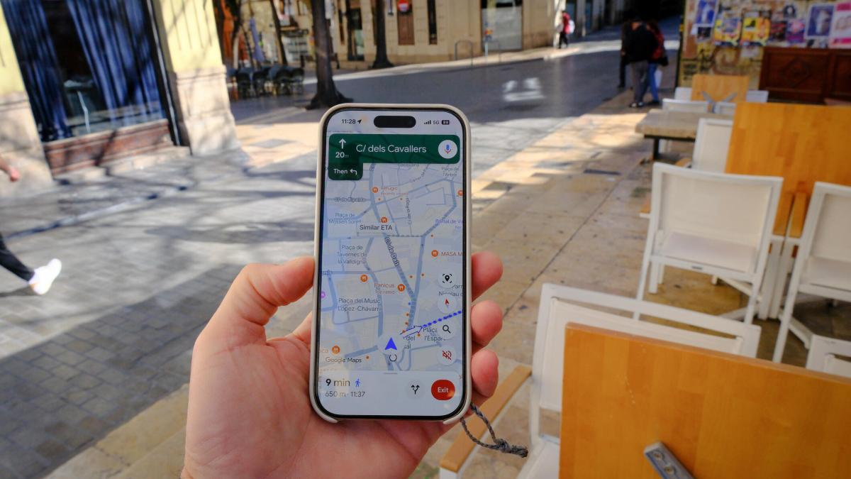 A phone held showing Google Maps while walking down the street.
