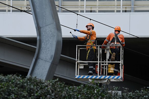 Rail repair staff work on overhead wires near Chatswood station on Tuesday morning. 