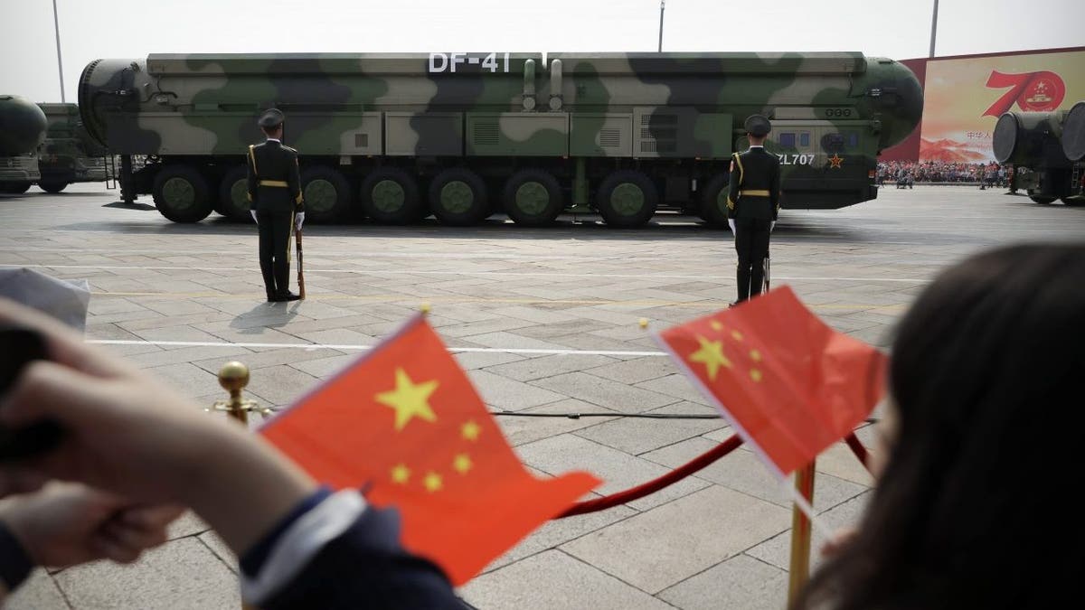 Spectators wave Chinese flags as military vehicles carrying DF-41 nuclear ballistic missiles roll during a parade in Beijing on Oct. 1, 2019.