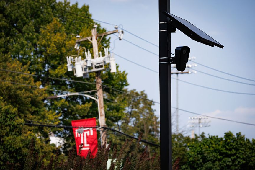A Flock camera and solar panel next to power lines.