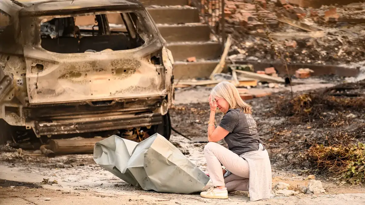 Woman mournes next to burned home