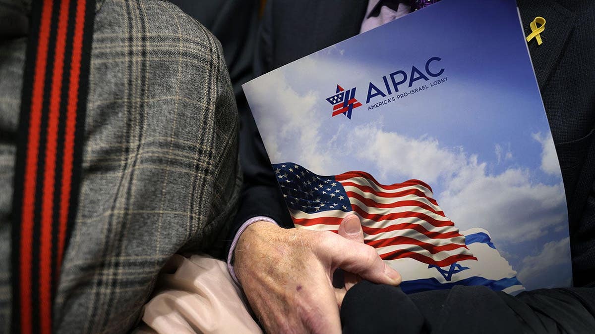 A visitor holding an AIPAC folder inside an elevator at Rayburn House Office Building.