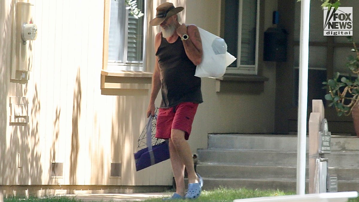 Brian Hooker walks home carrying collected trash in California.