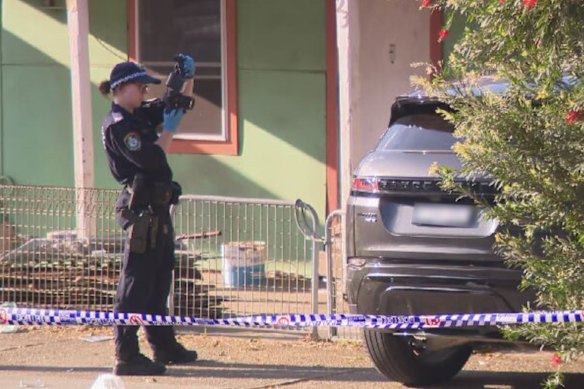 A forensic officer photographs the black Range Rover on Tuesday afternoon.