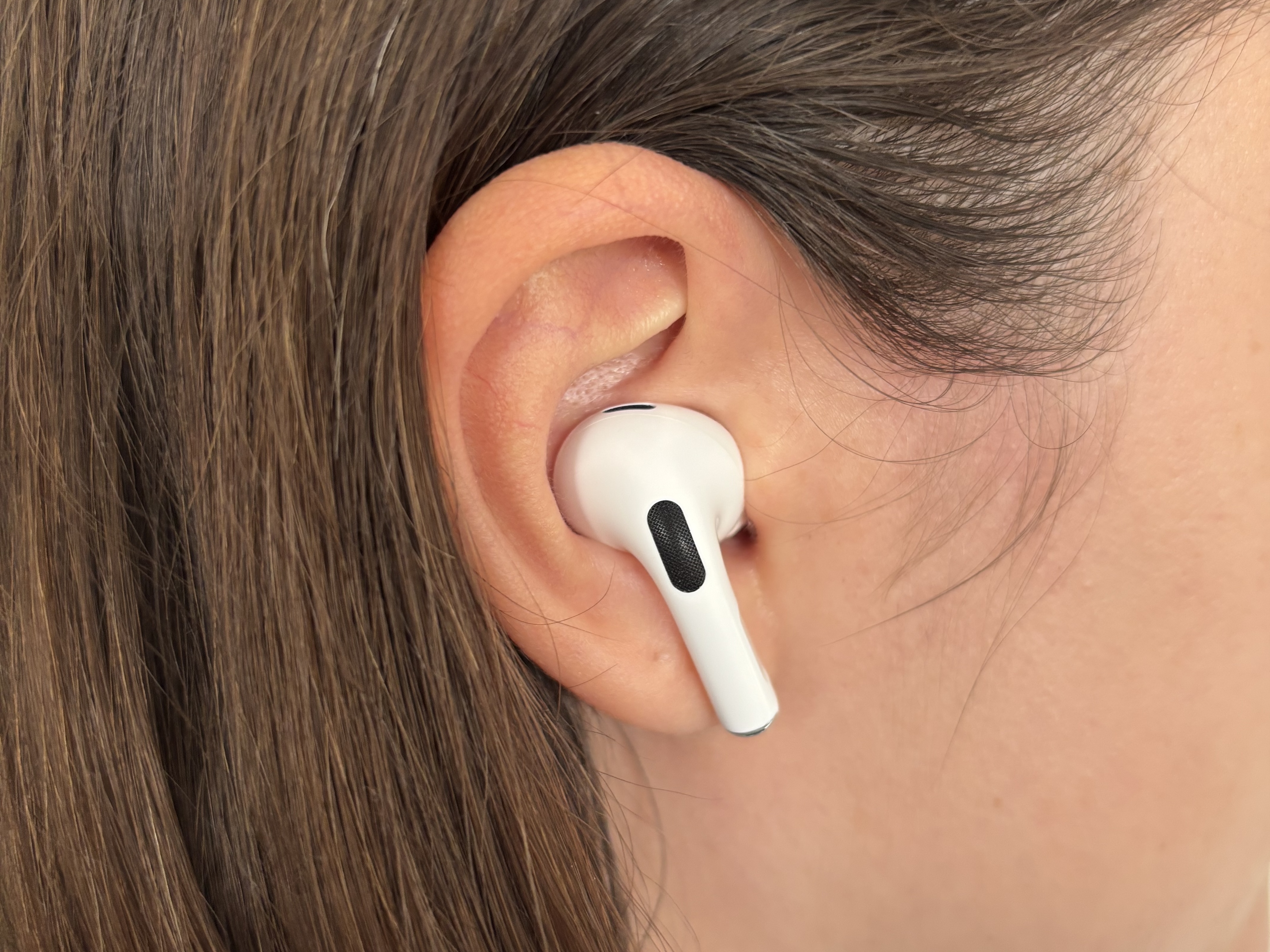 The AirPods Pro 2 in an ear surrounded by light brown hair.