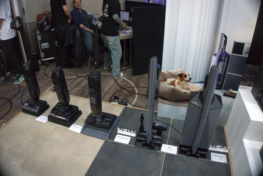 Line up of different Narwal vacuums. One has a poster behind it featuring a dog to indicate these vacuums work for home with pets.