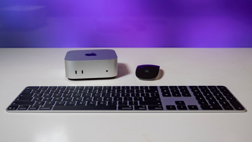 mac mini sitting next to a black magic mouse and behind a magic keyboard.