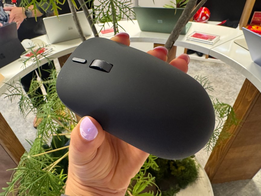 hand holding a mouse with just one button and a scroll wheel, with a matte black finish